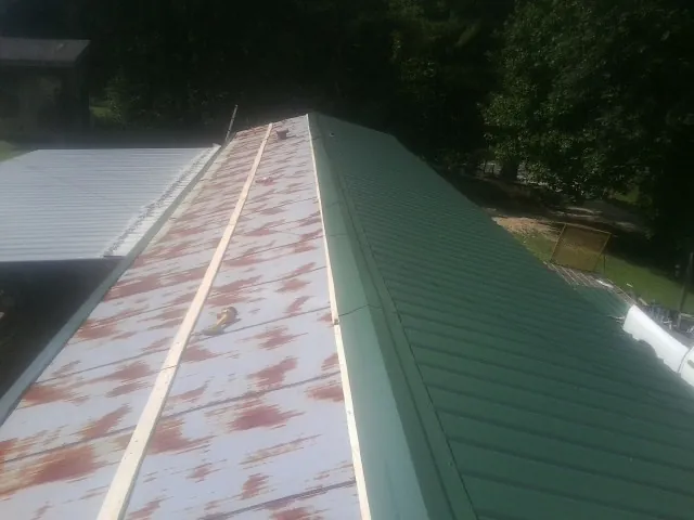 Old rusted panels beside newly installed green metal roofing — Wind Damage Roof Repair by Roofing Brothers in Lockport