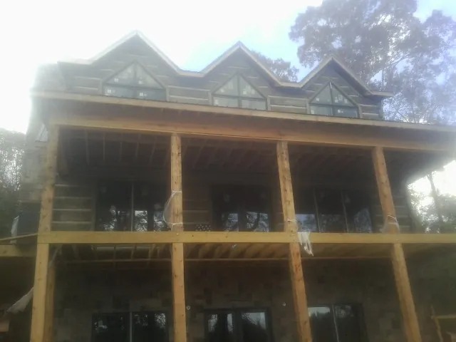Dormers and porch framing on a large log home under construction — Roof Coating work by our crew in Lockport