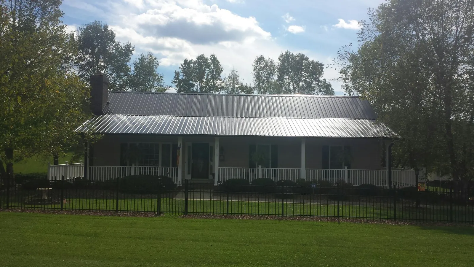 Gray metal roof on a brick ranch with a full width front porch — Gutter Guard Installation work by our crew in Lockport
