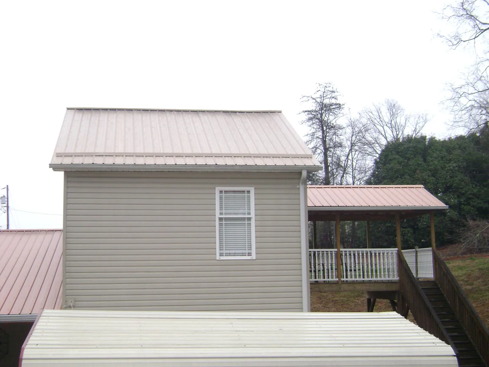 Tan metal roofs on a two story addition and attached porch, from a Roof Replacement job in Lockport